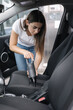 © Aleksandr - Female using portable vacuum cleaner in her car. Electrical vacuum in woman's hand clean car inside from dust. Self servise car wash