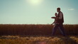 Agronomists team walking wheat field on sunny day. Summer harvesting season.