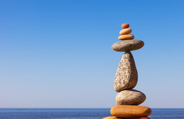 Wall Mural - Rock zen Pyramid of balanced stones against the background of the sea and blue sky.