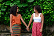 © PICHA - Happy lesbian couple holding hands in the park