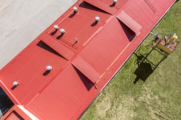 Wall Mural - red corrugated metal roof with installed pipes of ventilation systems. aerial overhead view.