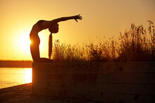 Silhouette Woman With Yoga Posture On The Beach Pier At Sunset Or Sunrise