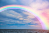 Fototapeta Tęcza - Beautiful view of colorful rainbow in sky over sea