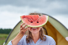 Funny Woman Eating Watermelon On A Picnic. Girl Closed Her Eyes With A Watermelon, Looking Into The Holes
