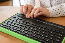 A Blind Woman Uses A Computer With A Braille Display And A Computer Keyboard. Inclusive Device.