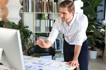 Sticker - Young modern business man analyzing data using computer while working in the office.