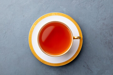 Tea in white cup with gold rim. Grey background. Close up. Top view.