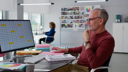 Portrait of mature art director working with table on computer in creative office