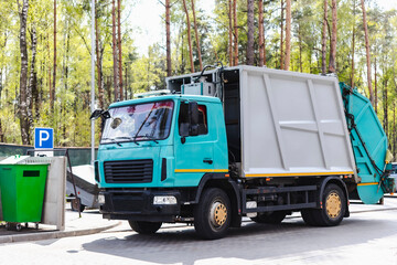 Fototapete - A garbage truck picks up garbage in a residential area. Loading mussar in containers into the car. Separate collection and disposal of garbage. Garbage collection vehicle.