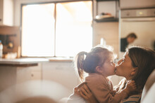 Young Woman Kissing Daughter At Home