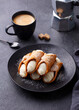 Cannoli Italian dessert on a plate with cup of coffee. Grey background.