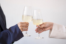 Hands Of Women Toasting Wineglasses In Front Of White Wall