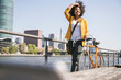 © Westend61 - Young businesswoman walking with bicycle by River Main on sunny day
