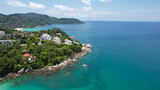 Fototapeta  - Clear water with a rocky Kata beach. The bottom is visible. Aerial view of the ocean and shore from the drone. The whole island is green. There are beautiful hotels. A tourist place in Thailand