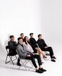 © Myron Muza - Group of six young boys and girls sitting on armchairs on a white background and thinking