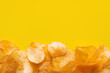 top view of delicious, crunchy and salty potato chips on yellow with copy space