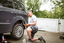 Middle Aged Man With Grey Hair Changes Tires On His Family Car Van
