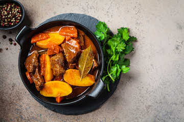 Wall Mural - Beef stew with potatoes, carrots in tomato sauce in black pot,  dark background.