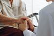 © Nattakorn - Closeup doctor holding senior patient hand for encouragement and empathy, medical trust and support concept