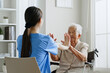 © Nattakorn - Young Asian woman nurse, caregiver assist a senior Asian woman to do physical therapy and exercise arms at home