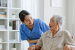 © Nattakorn - Young Asian woman, nurse, caregiver, carer of nursing home talking with senior Asian woman feeling happy at home