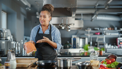 Wall Mural - TV Cooking Show in Restaurant Kitchen: Portrait of Black Female Celebrity Chef Talks, Teaches Fun Way How to Cook Food. Online Video Courses, Learning Video Lectures. Healthy Dish Recipe Preparation