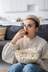 Wall Mural - astonished woman watching tv and eating popcorn at home