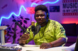 © AnnaStills - Young African American man wearing headphones adjusting microphone to start podcast or broadcast recording in home studio