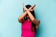 Young hispanic woman isolated on blue background keeping two arms crossed, denial concept.
