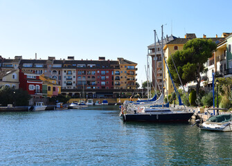 Jetty with yacht. Yachts and motor boats in marina Port Saplaya, Valencia. Yacht and fishing motorboat in yacht club. Colourful houses with apartments at coast Mediterranean Sea. Sailboat near pier.