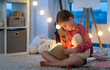 © Ievgen Skrypko - Little beautiful girl reads a fairy tale before slleping with flashlight and Teddy bear. Child sitting in the children bedroom with book. Evening reading with garland