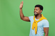 Young smiling happy cheerful friendly fun man of African American ethnicity 20s wear blue t-shirt waving hand say hello hi isolated on plain green background studio portrait. People lifestyle concept.