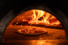 Pizza Concept. Preparing Traditional Italian Pizza. Long Shovel For Pizza, Baking Dough In A Professional Oven With Open Fire In Interior Of Modern Restaurant Kitchen