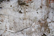 An old concrete wall with remnants of gray paint crumbling from time. Texture of eroded concrete.