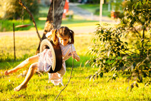 Young Country Girl Playing Alone Outdoors On Tyre Swing