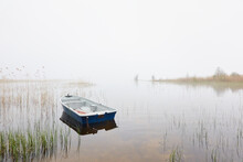 Small Fishing Boat Anchored In A Forest Lake. Fog, Rain. Reflections On Water. Transportation, Traditional Craft, Recreation, Leisure Activity, Healthy Lifestyle, Local Tourism Theme. Spring Landscape