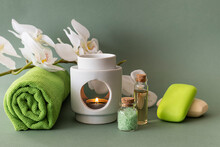 Spa Kit With Sea Salt, Body Oil And Fragrant Soap On A Green Background. A Bath Towel And A Sprig Of Orchid In The Background. Light Green Background