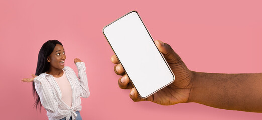 Surprised black lady showing big white empty smartphone screen