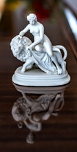 Purchased White Porcelain Figurine Of A Girl On A Lion Close-up On The Background Of A Piano Cover