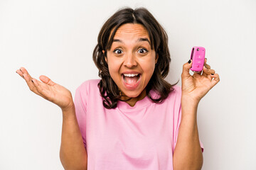 Wall Mural - Young hispanic woman holding car keys isolated on white background receiving a pleasant surprise, excited and raising hands.