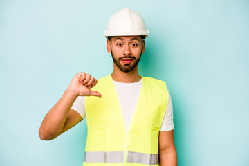 Wall Mural - Young laborer hispanic man isolated on blue background showing a dislike gesture, thumbs down. Disagreement concept.