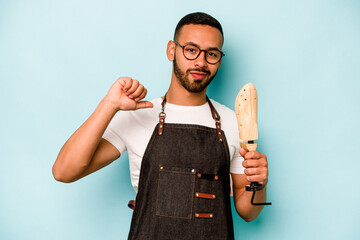 Wall Mural - Young hispanic shoemaker man isolated on blue background feels proud and self confident, example to follow.