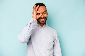 Wall Mural - Young hispanic man isolated on blue background excited keeping ok gesture on eye.