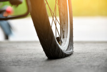 Closeup View Of Rear Flat Tire Of Vintage Bicycle Which Parked On Pavement Beside The Road. Soft And Selective Focus.