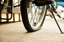 Closeup View Of Rear Flat Tire Of Vintage Bicycle Which Parked On Pavement Beside The Road. Soft And Selective Focus.