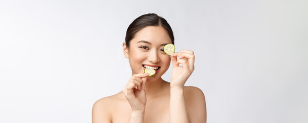 Wall Mural - Natural homemade fresh cucumber facial eye pads facial masks. Asian woman holding cucumber pads and smile relax with natural homemade