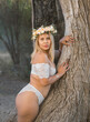 Latina fairy nymph in white with flowers in hair poses inside a giant old tree