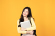 Portrait of happy casual Asian girl student with backpack and laptop isolated on yellow background. Back to school and learning concept.