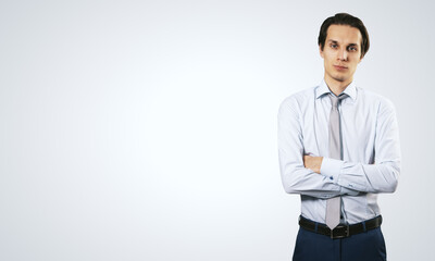 Poster - Business success concept with young smiling businessman folding his hands in white shirt and dark blue trousers on abstract light blank background with place for your logo or text. Mock up