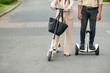 © DragonImages - Students or employees riding on campus on electric scooters and discussing news and projects
